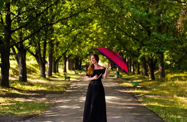 Meisje in een zwarte jurk met paraplu in het park — Stockfoto