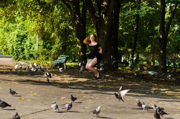 Menina em um vestido preto pulando no parque — Fotografia de Stock