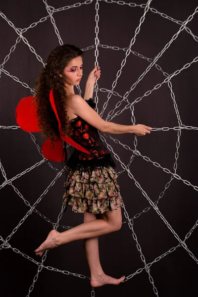 Girl dressed as butterfly in a web from chains