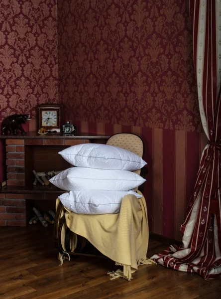 Качающее кресло с подушками возле камина — стоковое фото