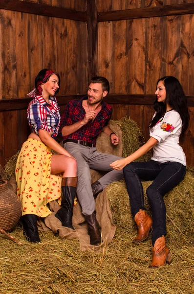Girls posing with a young guy in the hay — Stock Photo, Image