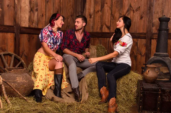 Girls posing with a young guy in the hay — Stock Photo, Image