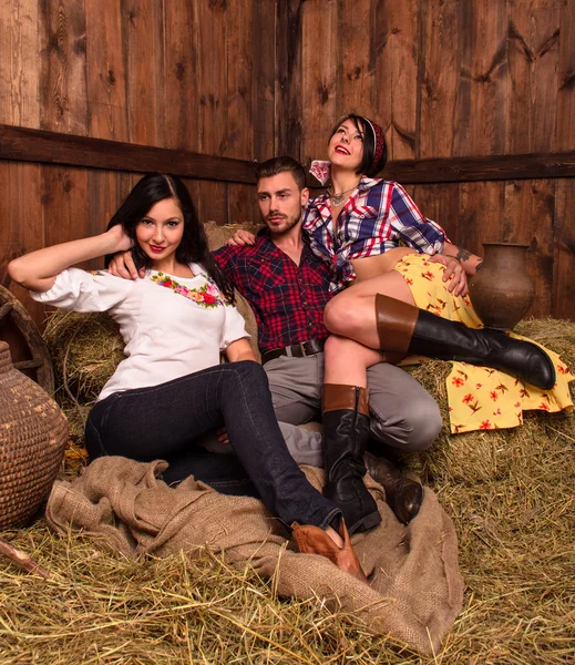 Girls posing with a young guy in the hay — Stock Photo, Image