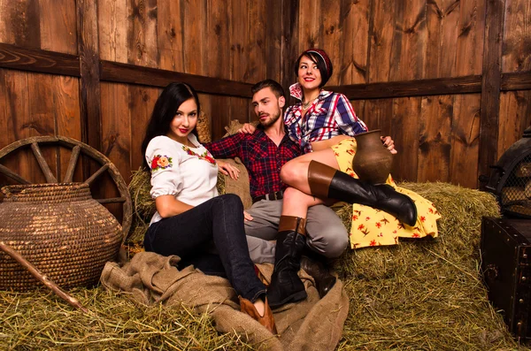 Girls posing with a young guy in the hay — Stock Photo, Image