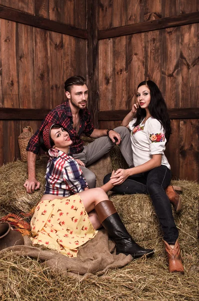 Girls posing with a young guy in the hay — Stock Photo, Image