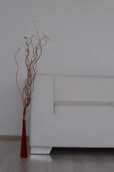Декоративная ваза с искусственными растениями возле дивана — стоковое фото