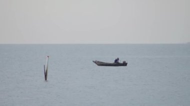 Denizde yüzen geleneksel balıkçı teknesi. Asyalı balıkçılar küçük bir teknede balık tutuyor. Balıkçının teknesi okyanusta yüzüyor. Deniz yüzeyinde dalgalanan balıkçı gemisi