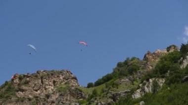 İnsanlar dağlarda yamaç paraşütü uçurur.