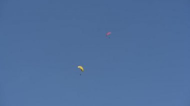 İnsanlar dağlarda yamaç paraşütü uçurur.