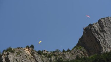 İnsanlar dağlarda yamaç paraşütü uçurur.