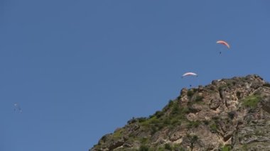 İnsanlar dağlarda yamaç paraşütü uçurur.