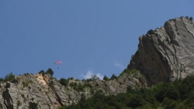 İnsanlar dağlarda yamaç paraşütü uçurur.