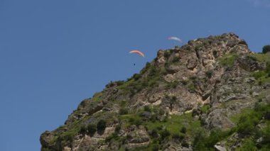 İnsanlar dağlarda yamaç paraşütü uçurur.