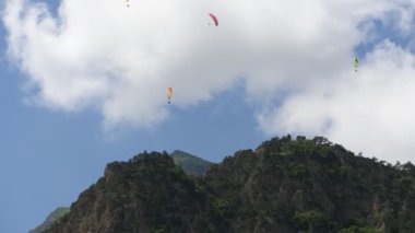 İnsanlar dağlarda yamaç paraşütü uçurur.