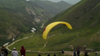İnsanlar dağlarda yamaç paraşütü uçurur.