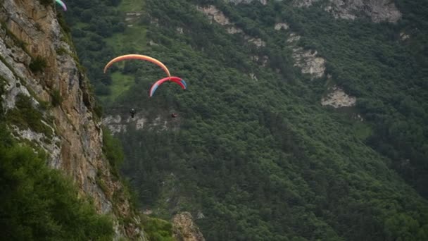 Menschen fliegen mit Gleitschirmen in die Berge — Stockvideo