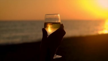 Gün batımında deniz kenarında bir bardak şarap. Seçici odak.