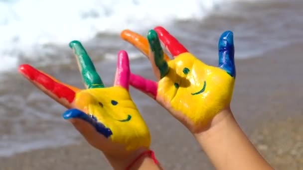 Ein Kind am Meer mit Farben auf den Händen lächelt. Selektiver Fokus. — Stockvideo