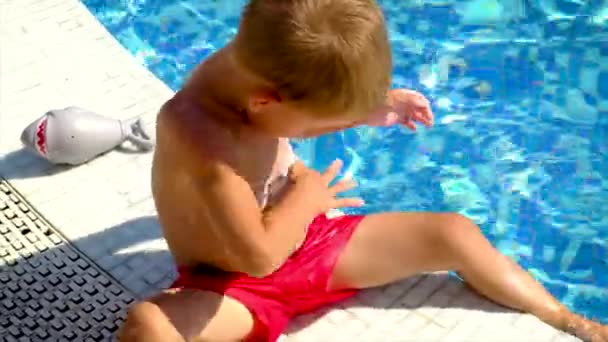 Un niño mancha protector solar junto a la piscina. Enfoque selectivo. — Vídeo de stock