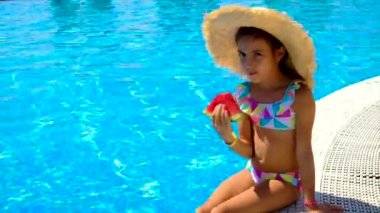 Çocuk havuzun yanında bir karpuz yiyor. Seçici odak.