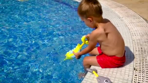 Un enfant dans la piscine éclabousse l'eau. Concentration sélective. — Video