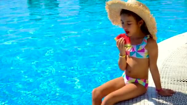 A criança come uma melancia perto da piscina. Foco seletivo. — Vídeo de Stock
