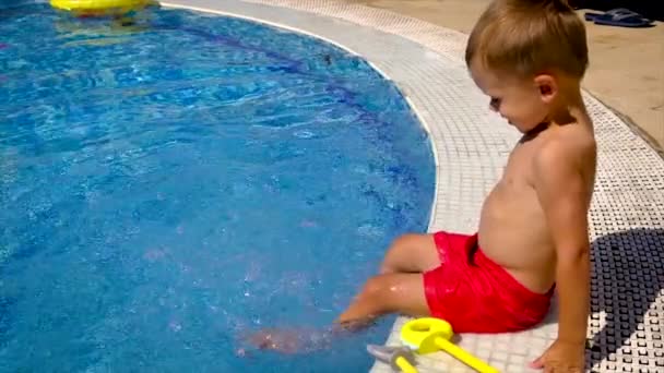 Ребёнок в бассейне брызгает водой. Селективный фокус. — стоковое видео