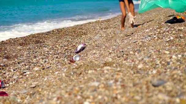 Un enfant ramasse les ordures sur la plage. Concentration sélective. — Video