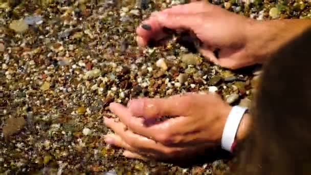 El hombre recoge piedras en el mar. Enfoque selectivo. — Vídeo de stock