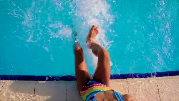 Ein Kind im Pool spritzt Wasser. Selektiver Fokus. — Stockvideo