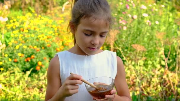 Het kind eet honing in de tuin. Selectieve focus. — Stockvideo
