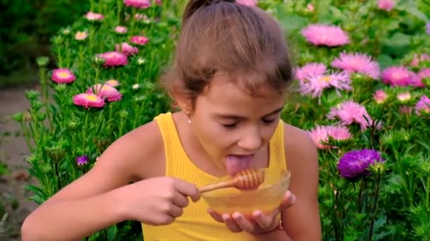Ребенок ест мед в саду. Селективный фокус. — стоковое видео