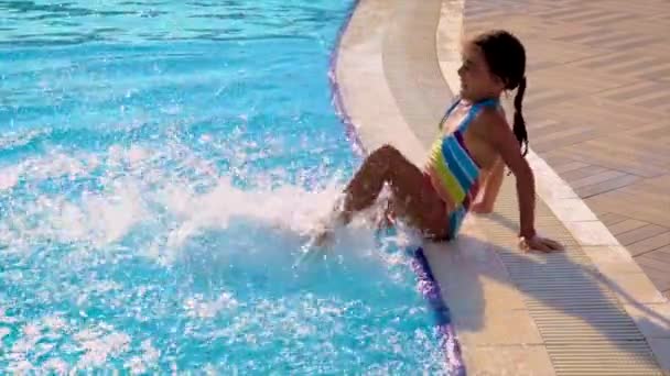 Ein Kind im Pool spritzt Wasser. Selektiver Fokus. — Stockvideo