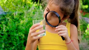 Çocuk suyu bir büyüteçle inceliyor. Seçici odak.