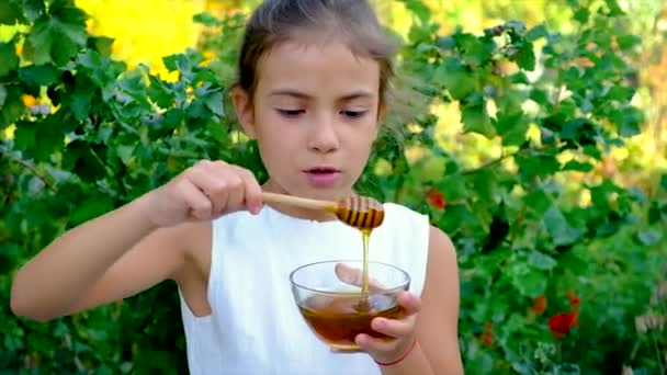 L'enfant mange du miel dans le jardin. Concentration sélective. — Video