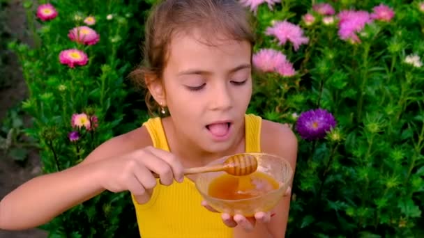 El niño come miel en el jardín. Enfoque selectivo. — Vídeos de Stock