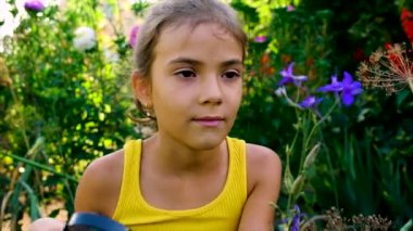 Çocuk bitkileri büyüteçle inceliyor. Seçici odak.