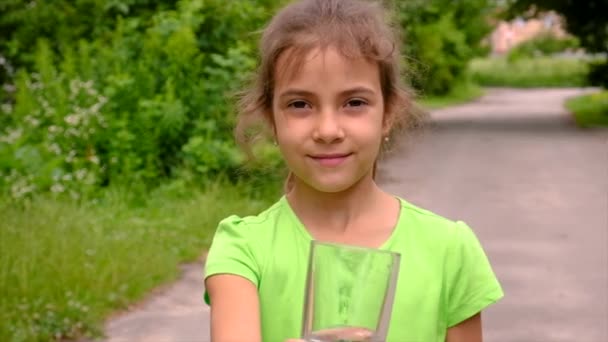 Das Kind trinkt Wasser aus einem Glas. Selektiver Fokus. — Stockvideo