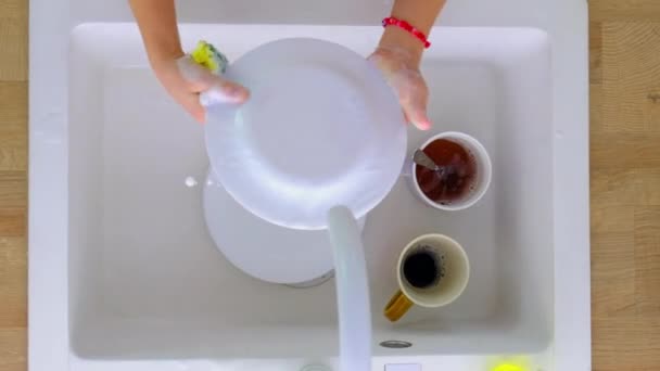 L'enfant lave la vaisselle dans la cuisine. Concentration sélective. — Video