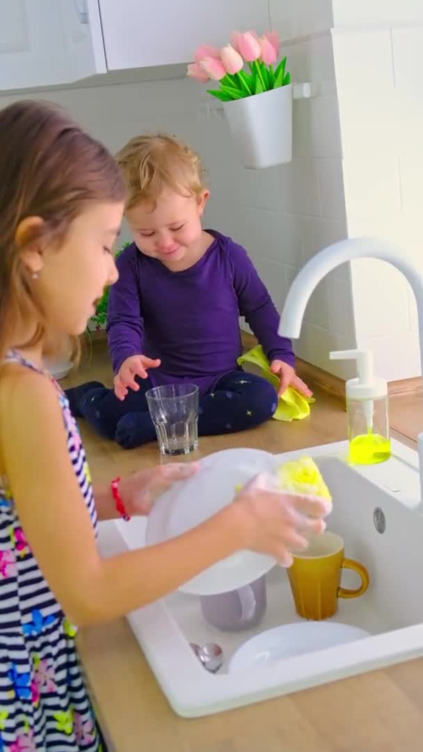 Ребенок моет посуду на кухне. Селективный фокус. — стоковое видео