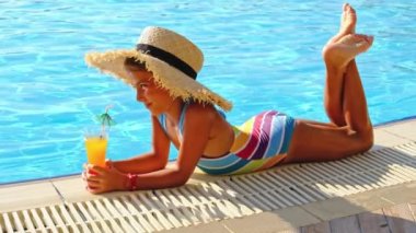 Çocuk havuz kenarında bir kokteyl içiyor. Seçici odak.