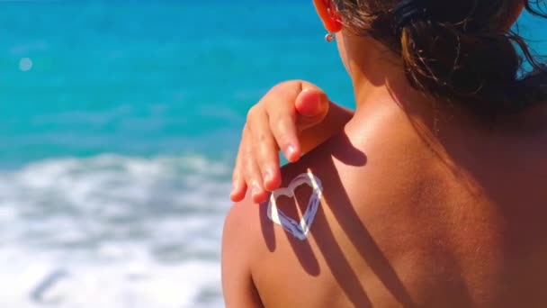 The child puts sunscreen on her back. Selective focus. — Vídeo de Stock