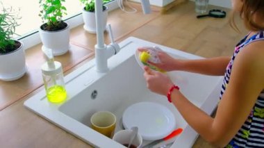 Çocuk mutfakta bulaşıkları yıkar. Seçici odak.