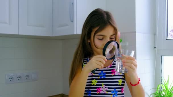 子供は虫眼鏡で水を調べます。選択的焦点. — ストック動画