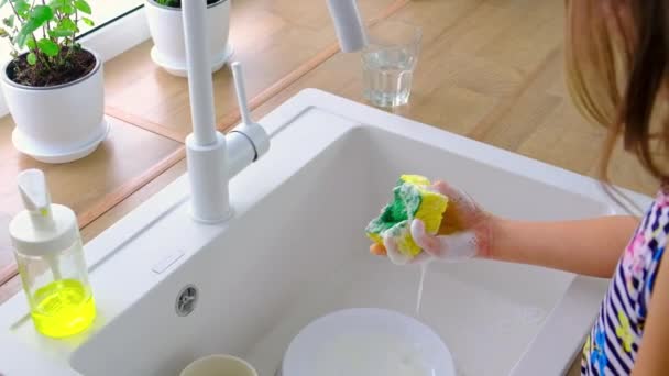 L'enfant lave la vaisselle dans la cuisine. Concentration sélective. — Video