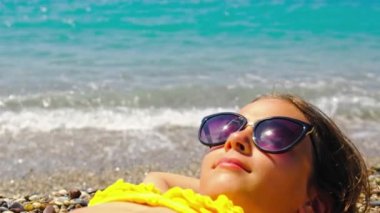 Bir çocuk plajda güneş gözlüğü ile güneşleniyor. Seçici odak.