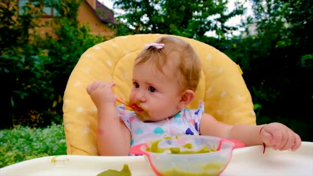 Ребенок ест пюре из брокколи. Селективный фокус. — стоковое видео