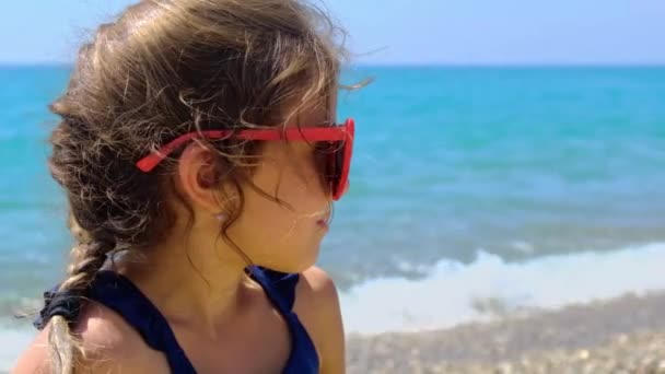 Ett barn solar på stranden i solglasögon. Selektiv inriktning. — Stockvideo