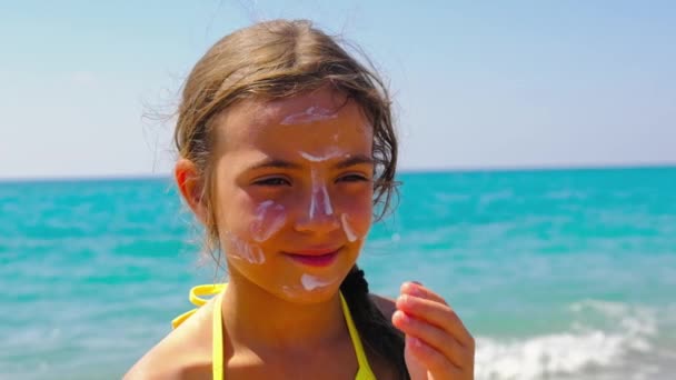 Barnet sätter solkräm på ansiktet. Selektiv inriktning. — Stockvideo