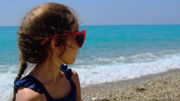 Bir çocuk plajda güneş gözlüğü ile güneşleniyor. Seçici odak. — Stok video